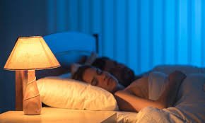 Pessoa dormindo tranquilamente em quarto escuro e confortável, representando boa qualidade do sono.